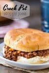 Crock Pot Sloppy Joes on a white plate next to a stack of wooden plates