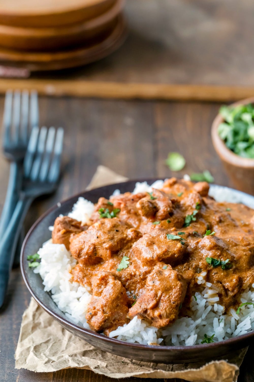 Indian Butter Chicken over rice in a dark brown dish 