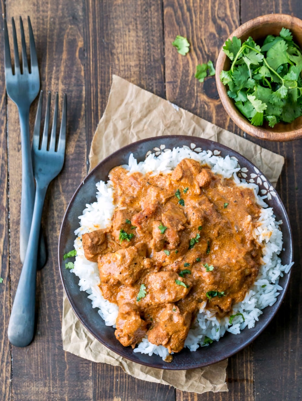 Dish of Indian Butter Chicken next to two dark metal forks