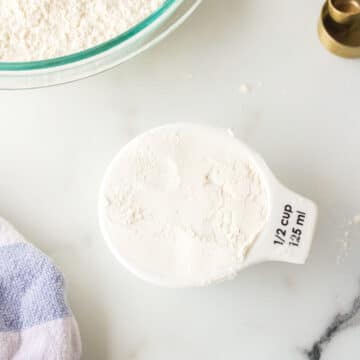 A measuring cup of self-rising flour next to a bowl.