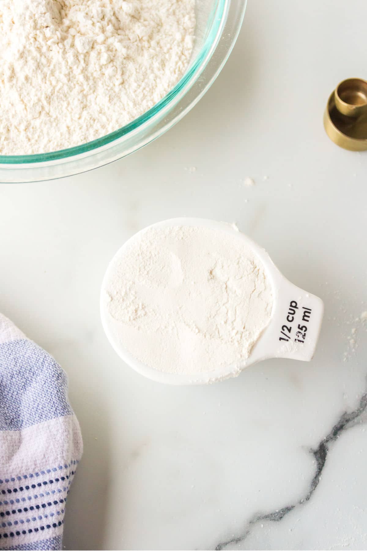 A measuring cup of self-rising flour next to a bowl. 