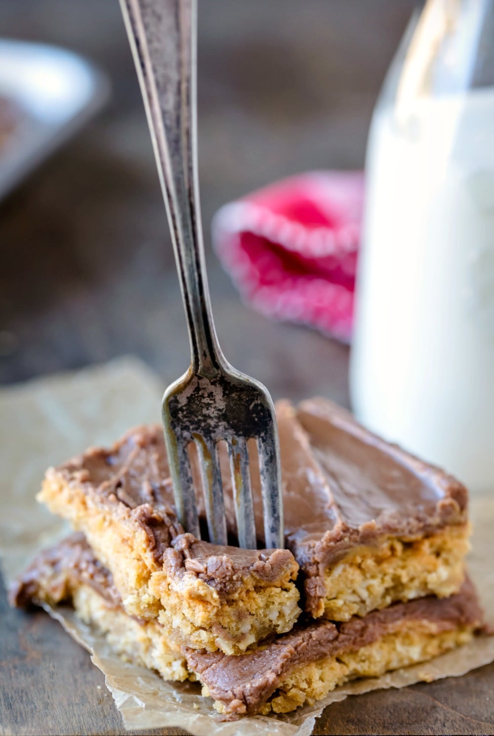 Two peanut butter bars stacked on top of each other with a fork in the top bar