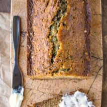 Zucchini bread on a marble cutting board next to a butter knife