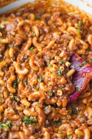 Scoop of homemade hamburger helper topped with chopped parsley