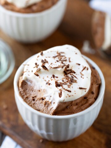 White porcelain cup filled with chocolate mousse and whipped cream