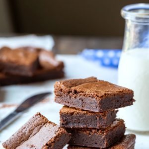 Stack of chewy fudge brownies next to a glass milk bottle