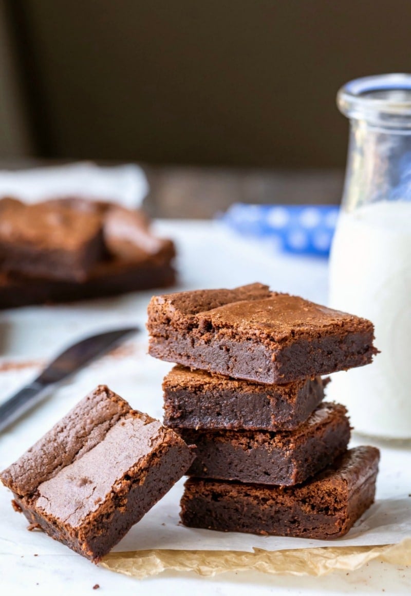 Stack of chewy brownies next to a glass milk bottle