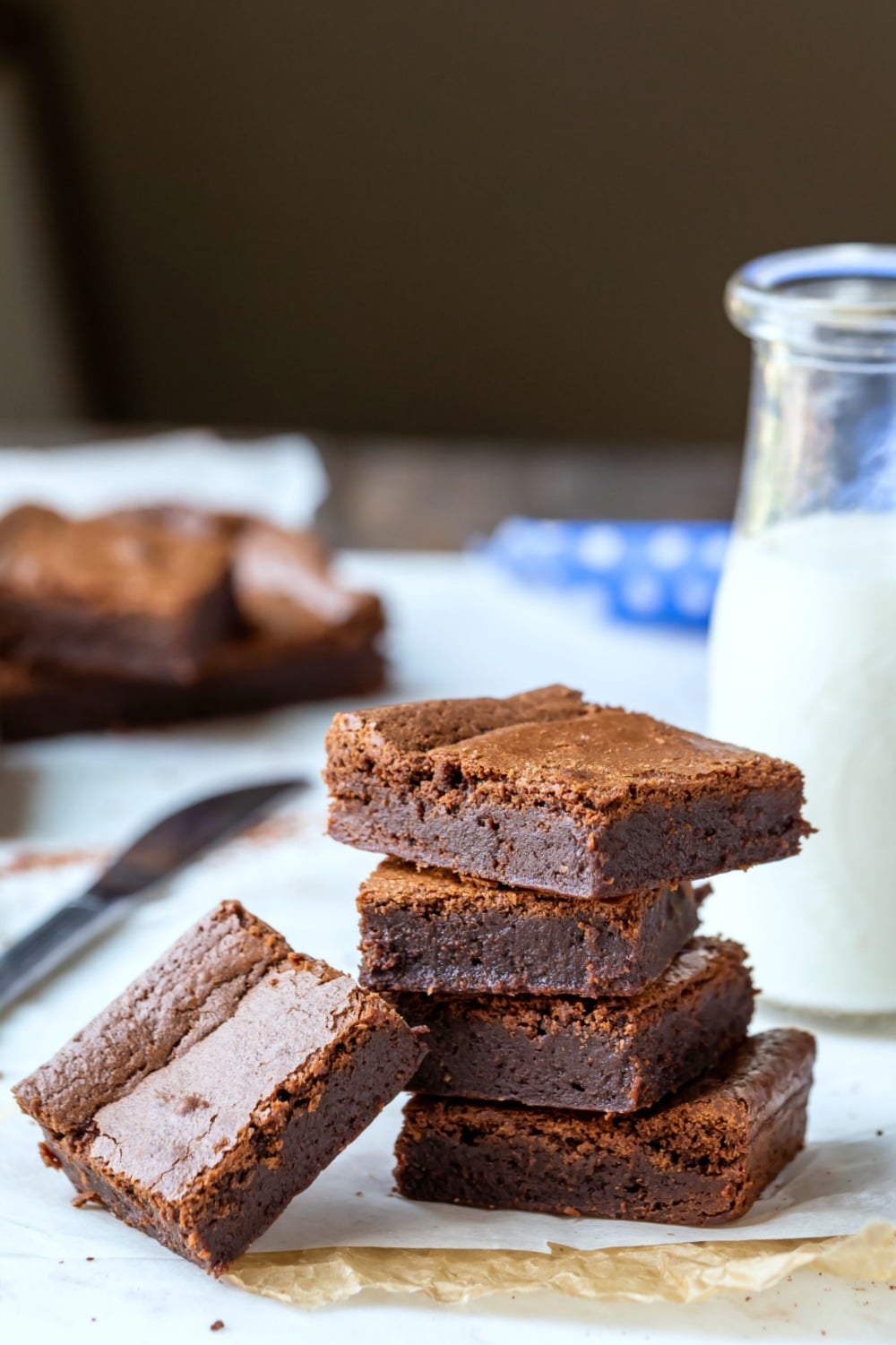 Stack of chewy fudge brownies next to a glass milk bottle