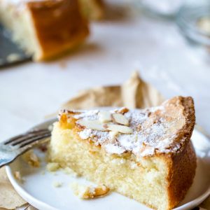 Slice of olive oil cake topped with powdered sugar and sliced almonds