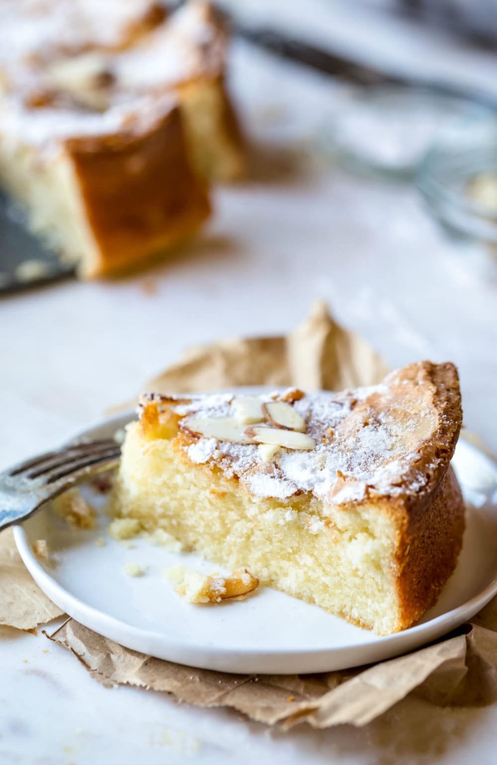 Slice of olive oil cake topped with powdered sugar and sliced almonds