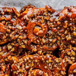 Close up photo of homemade sticky buns on a parchment lined baking tray.