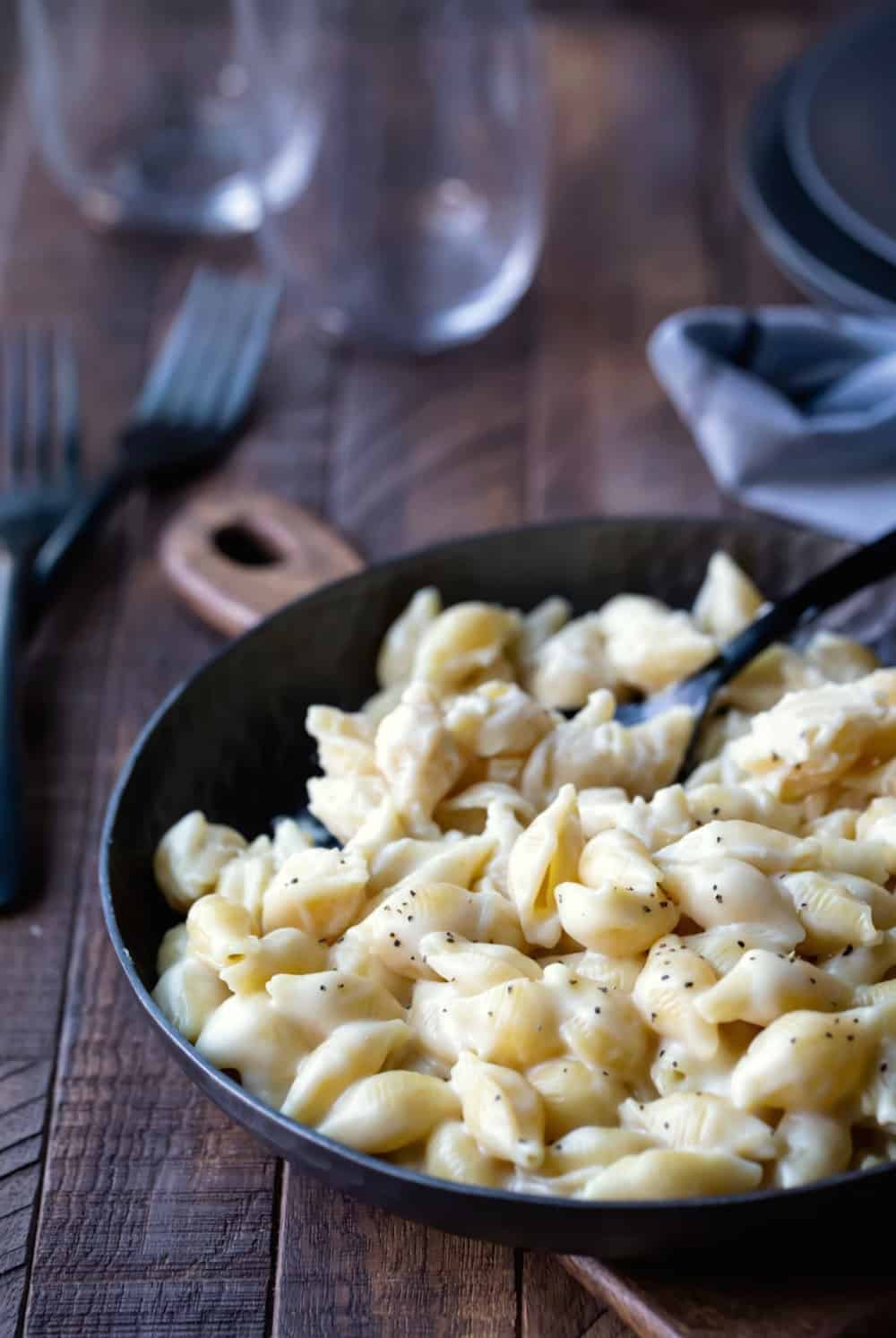 Homemade mac and cheese in a dark gray dish with a dark gray spoon