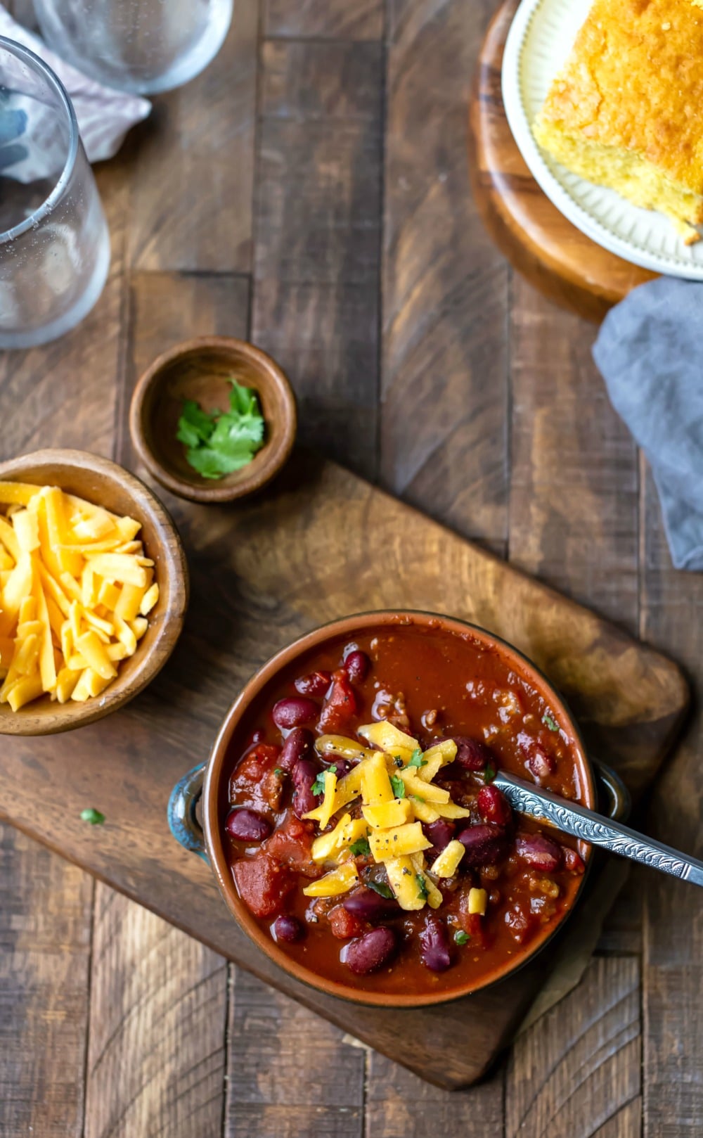 Crockpot chili in a bowl next to a bowl of cheese