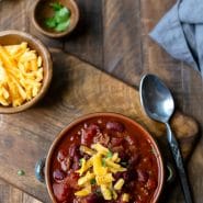 Crock of chili on a wooden cutting board