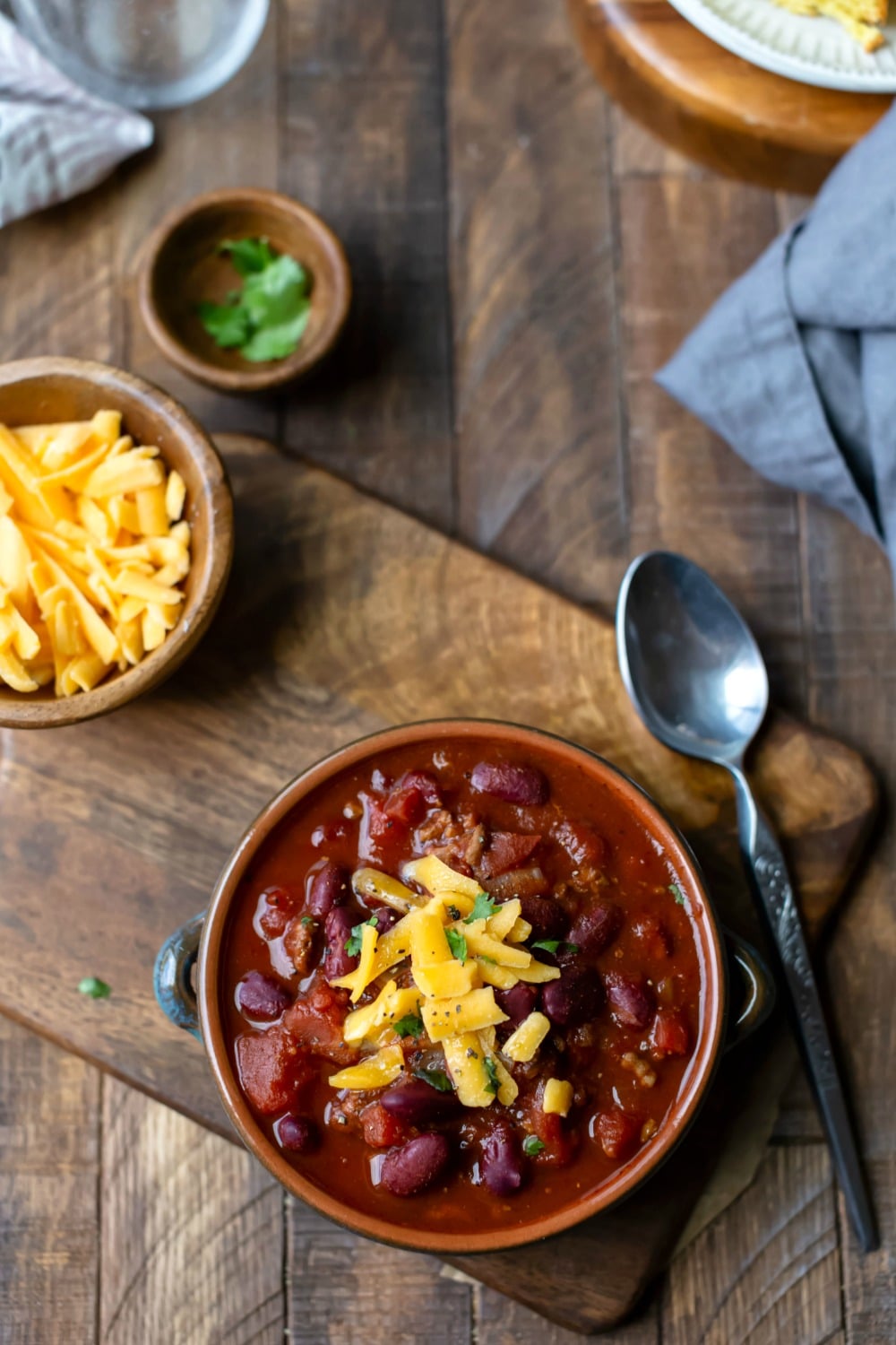 Bowl of crockpot chili on a wooden cutting board