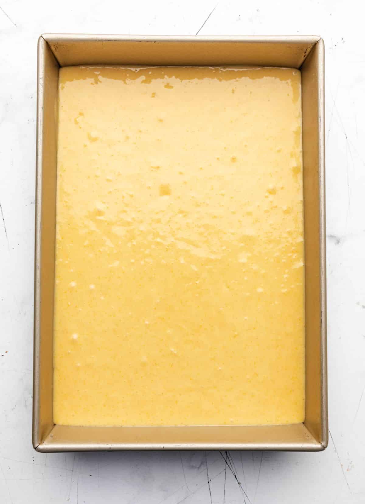 Sweet cornbread batter in a gold baking pan.