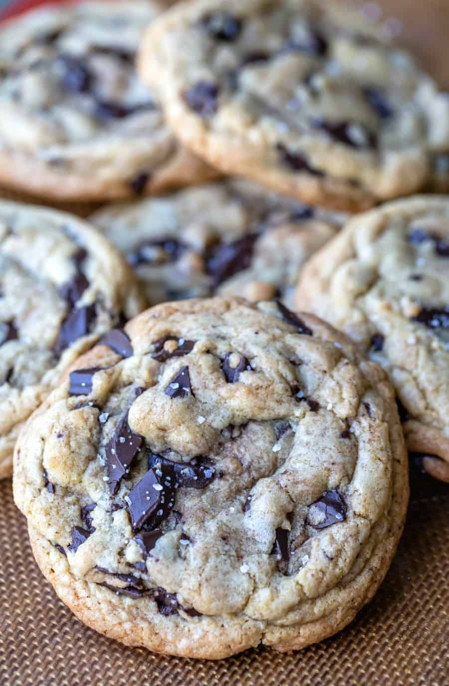 Thick homemade chocolate chip cookies in a pile on a baking mat