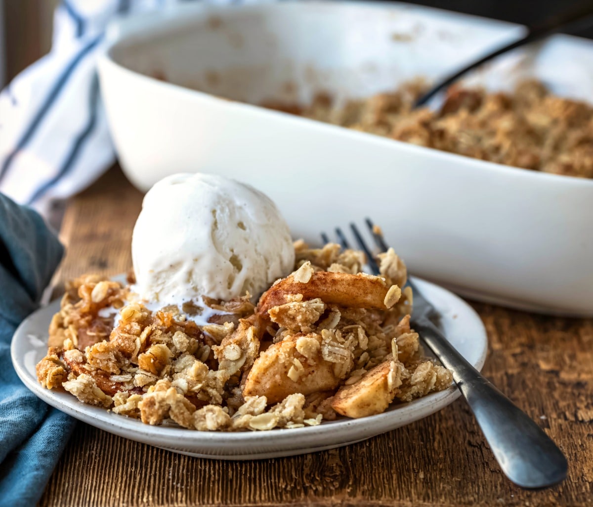 Dish of apple crisp with a black fork sitting on it