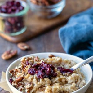 Instant pot steel cut oats in a white dish topped with dried cranberries