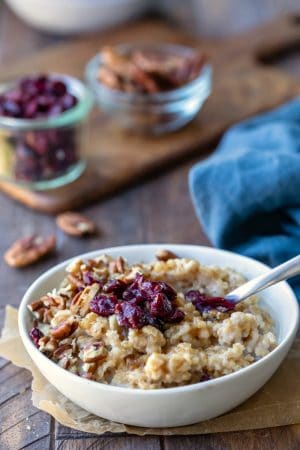 Instant pot steel cut oats in a white dish topped with dried cranberries
