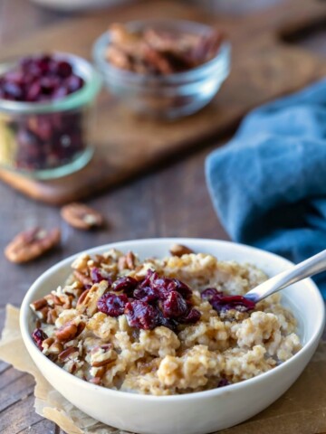 Instant pot steel cut oats in a white dish topped with dried cranberries