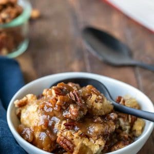 A dish of pecan pie pudding cake with a black spoon in it.