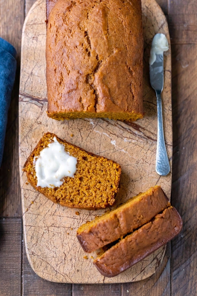 Partially buttered slice of pumpkin bread on a marble butting board
