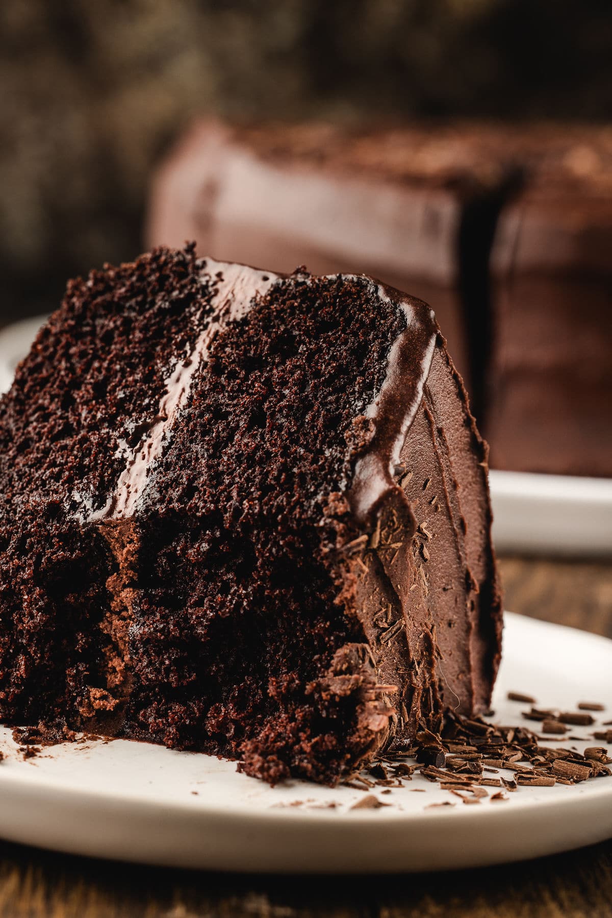 A piece of chocolate fudge cake on a plate with bites missing.