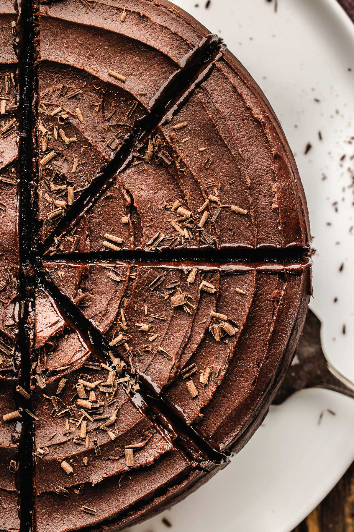 A sliced chocolate fudge cake with a server removing one piece.
