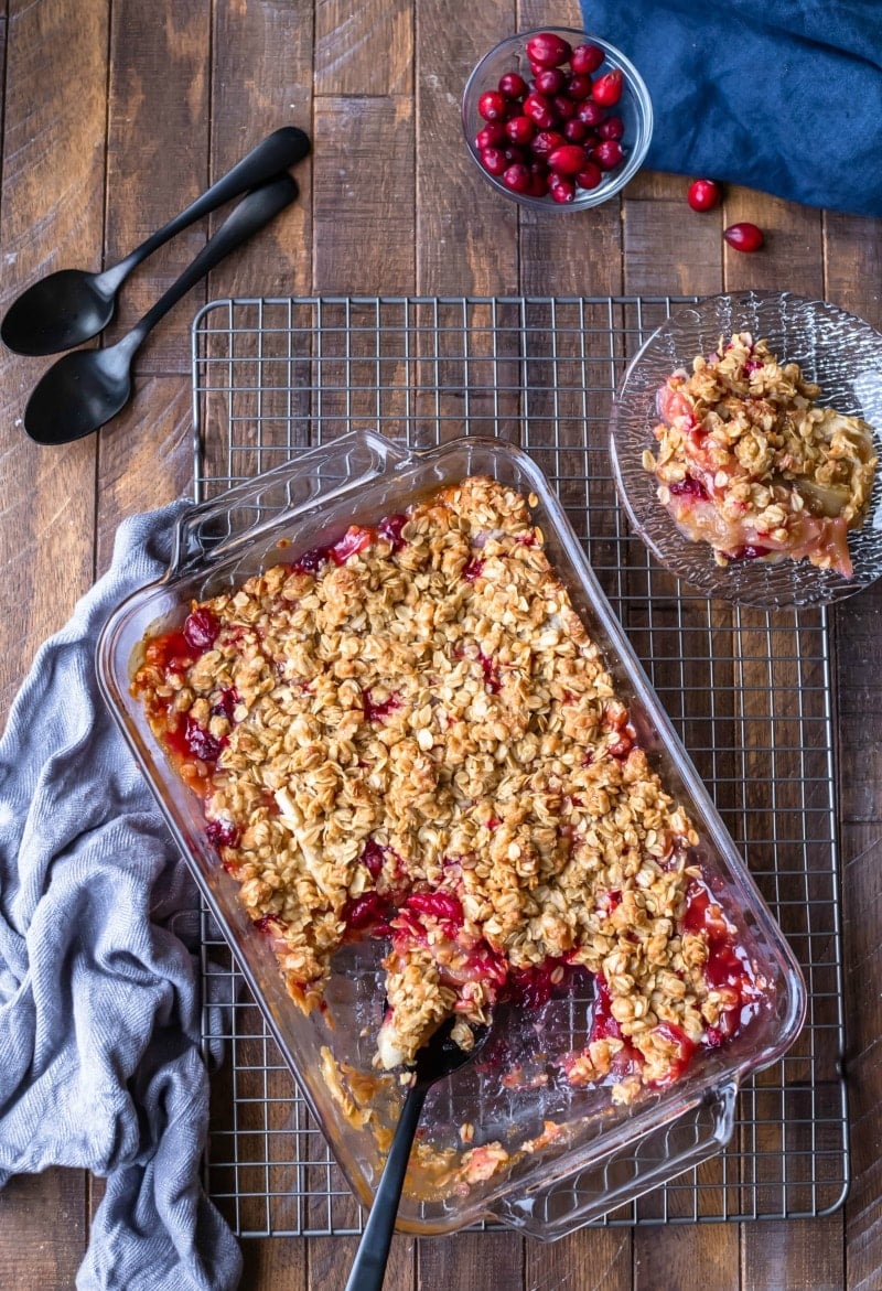 Glass dish with cranberry apple crisp next to a gray dish towel