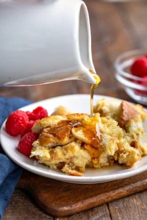 White carafe pouring maple syrup onto crock pot French toast