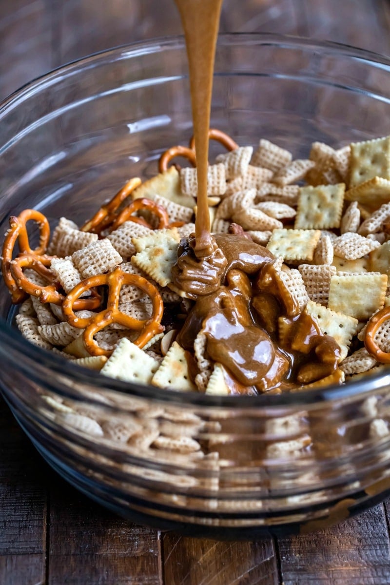 Toffee pouring onto bowl with Chex mix