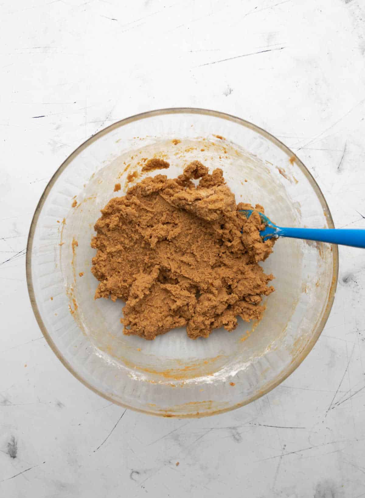 Molasses cookie dough in a glass mixing bowl. 