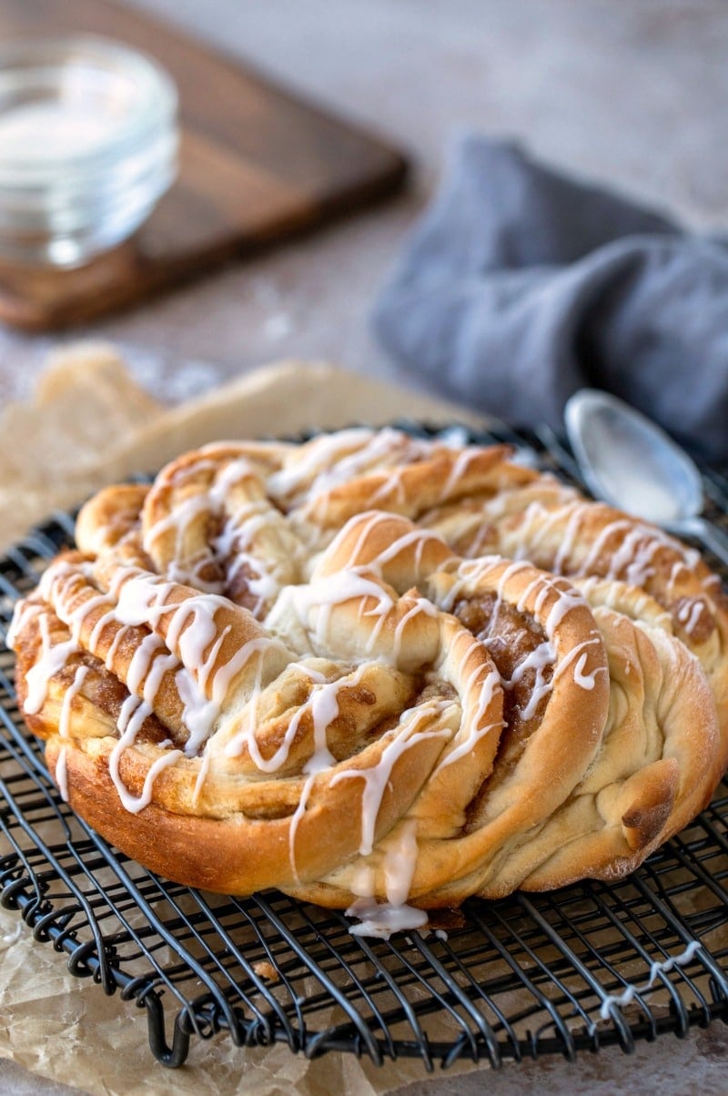 Braided cinnamon bread next to a spoon with icing on it