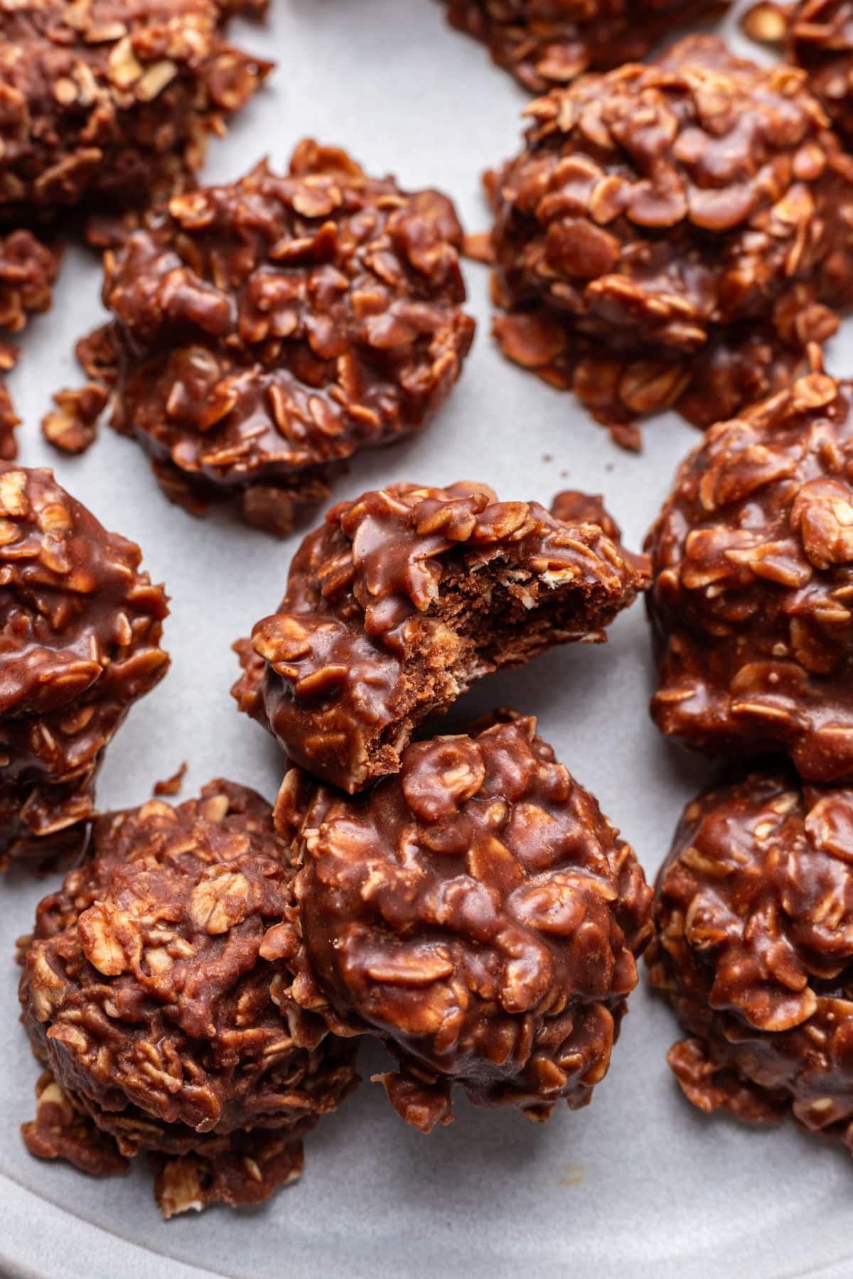 A plate of no bake cookies with one with a bite missing.