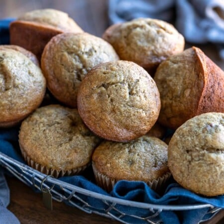 Basket of banana bread muffins on a wood cutting board