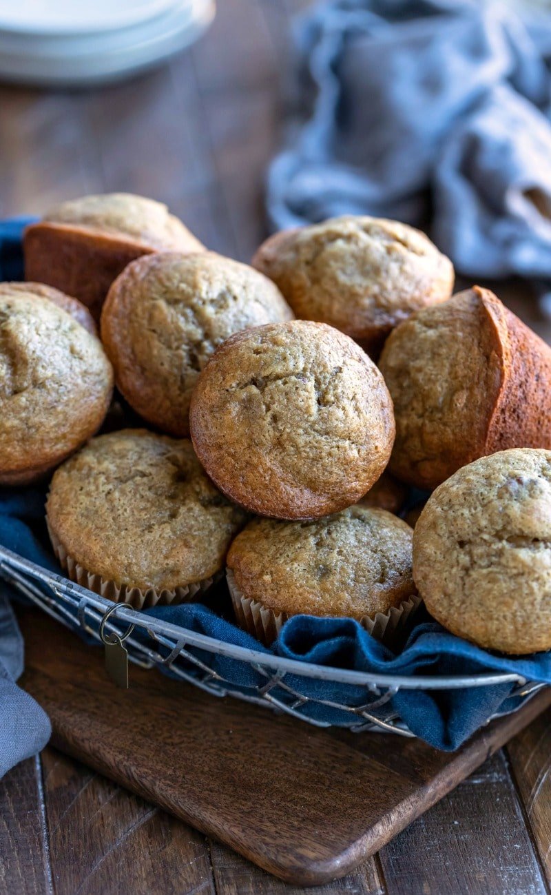 Basket of banana bread muffins on a wood cutting board