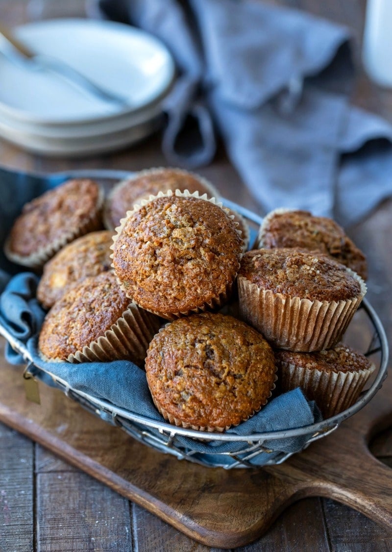 Basket of morning glory muffins on a wooden cutting board