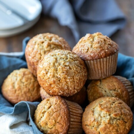 Maple brown sugar oatmeal muffins next to a stack of white plates
