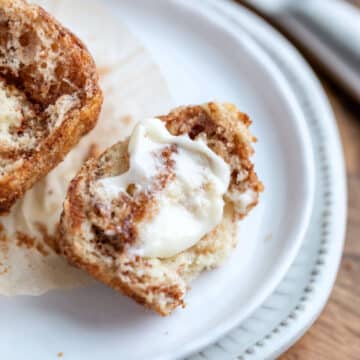 Buttered cinnamon muffin on a white plate.