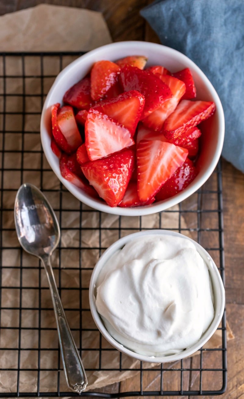 Bowl of whipped cream next to a bowl of strawberries