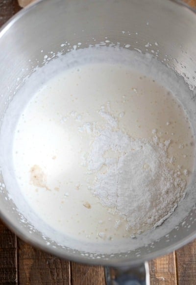 Powdered sugar and heavy whipping cream in a silver mixing bowl