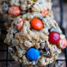 Monster cookies on a black metal cooling rack