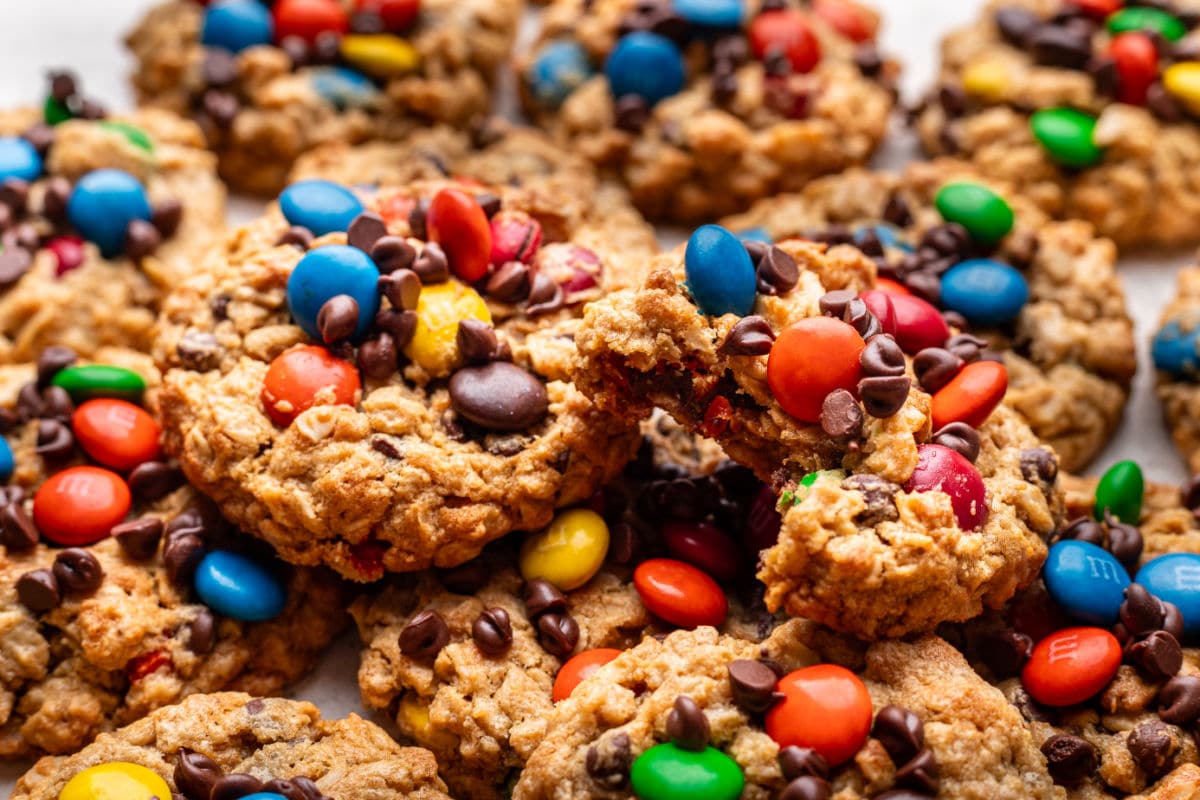 A monster cookie with a bite missing next on a stack of overlapping monster cookies.
