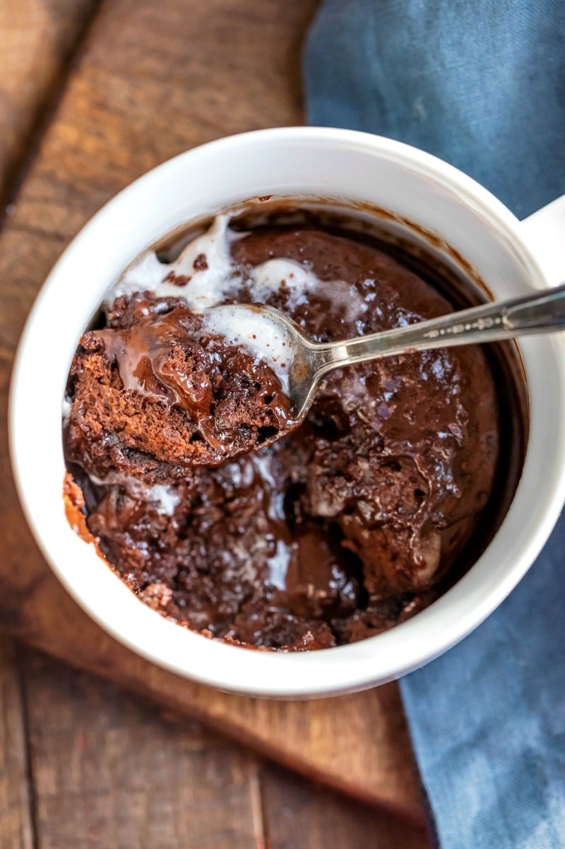 Spoon with molten chocolate mug cake on it in a white mug