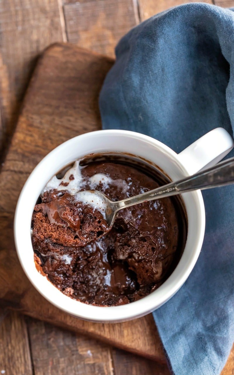 Molten chocolate mug cake in a white mug on a wooden cutting board