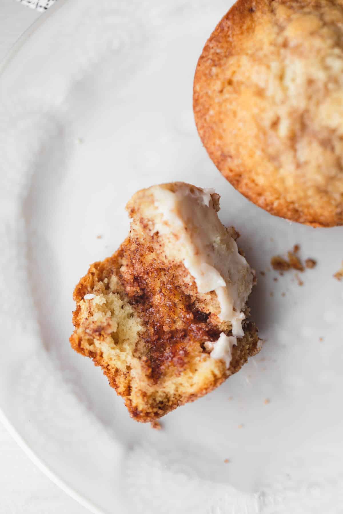 Part of a buttered cinnamon muffin on a white plate. 