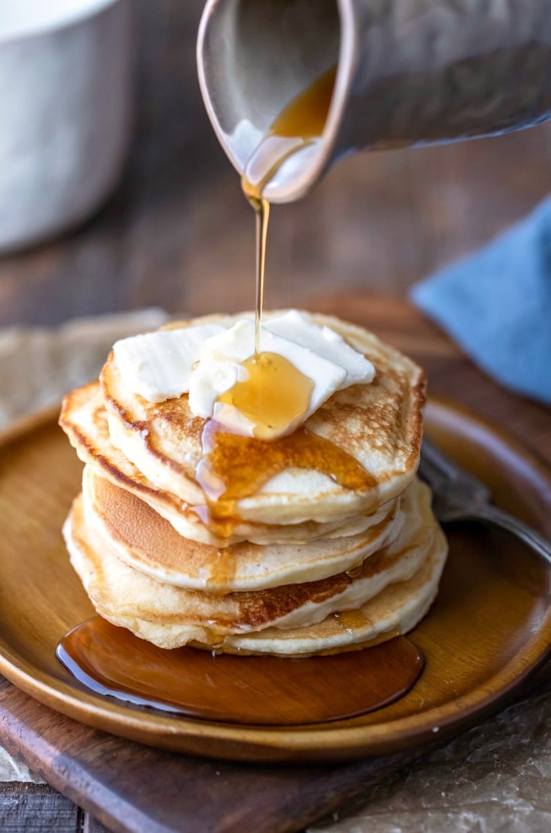 Maple syrup pouring onto sour cream pancakes