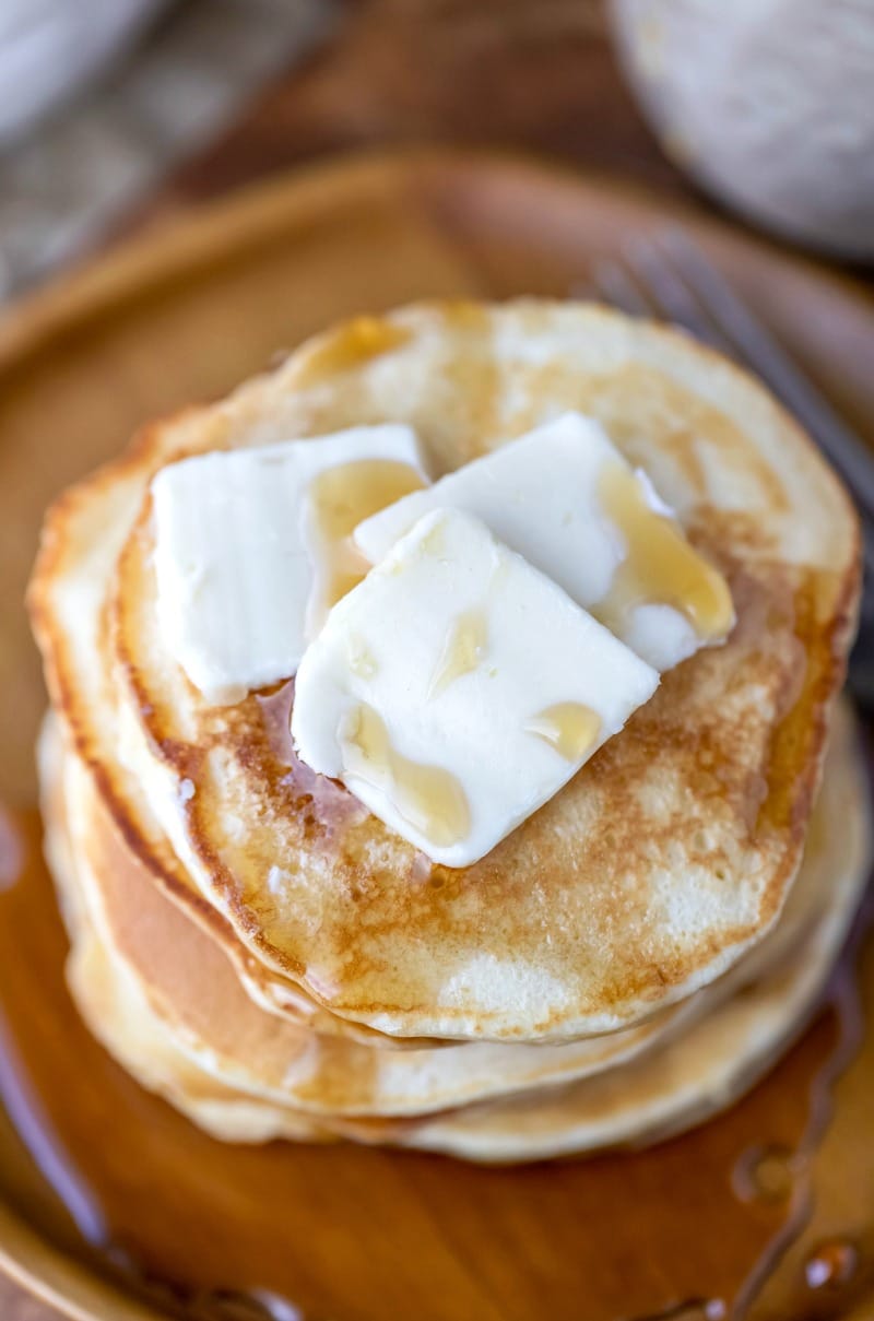 Close up photo of sour cream pancakes topped with butter pats