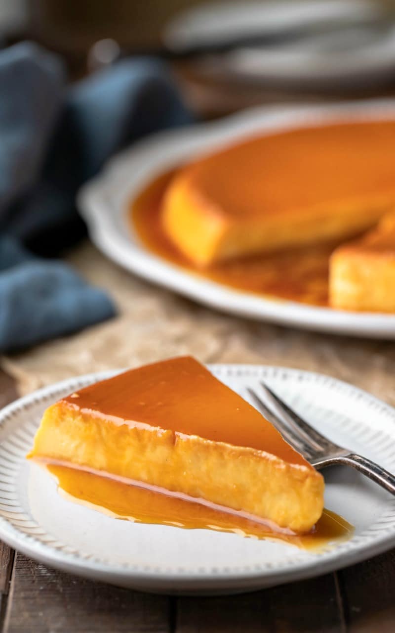 Slice of flan de queso on a plate next to a fork